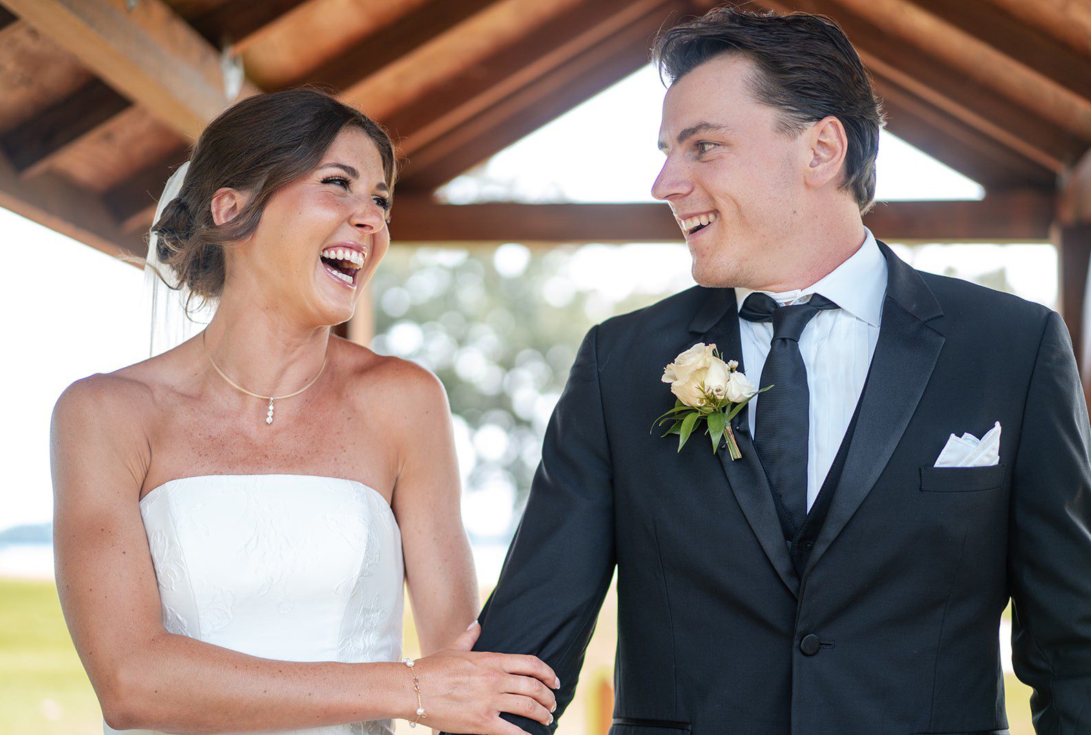 Bride and groom laughing together under the pergola, captured by Madison wedding photographers from Original Weddings at Bishops Bay Country Club