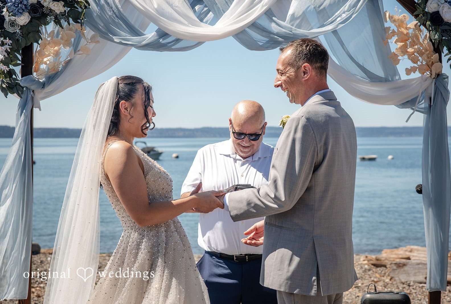 Couple exchanging rings by the water, captured by Seattle wedding photographers from Original Weddings at Mckees Beach