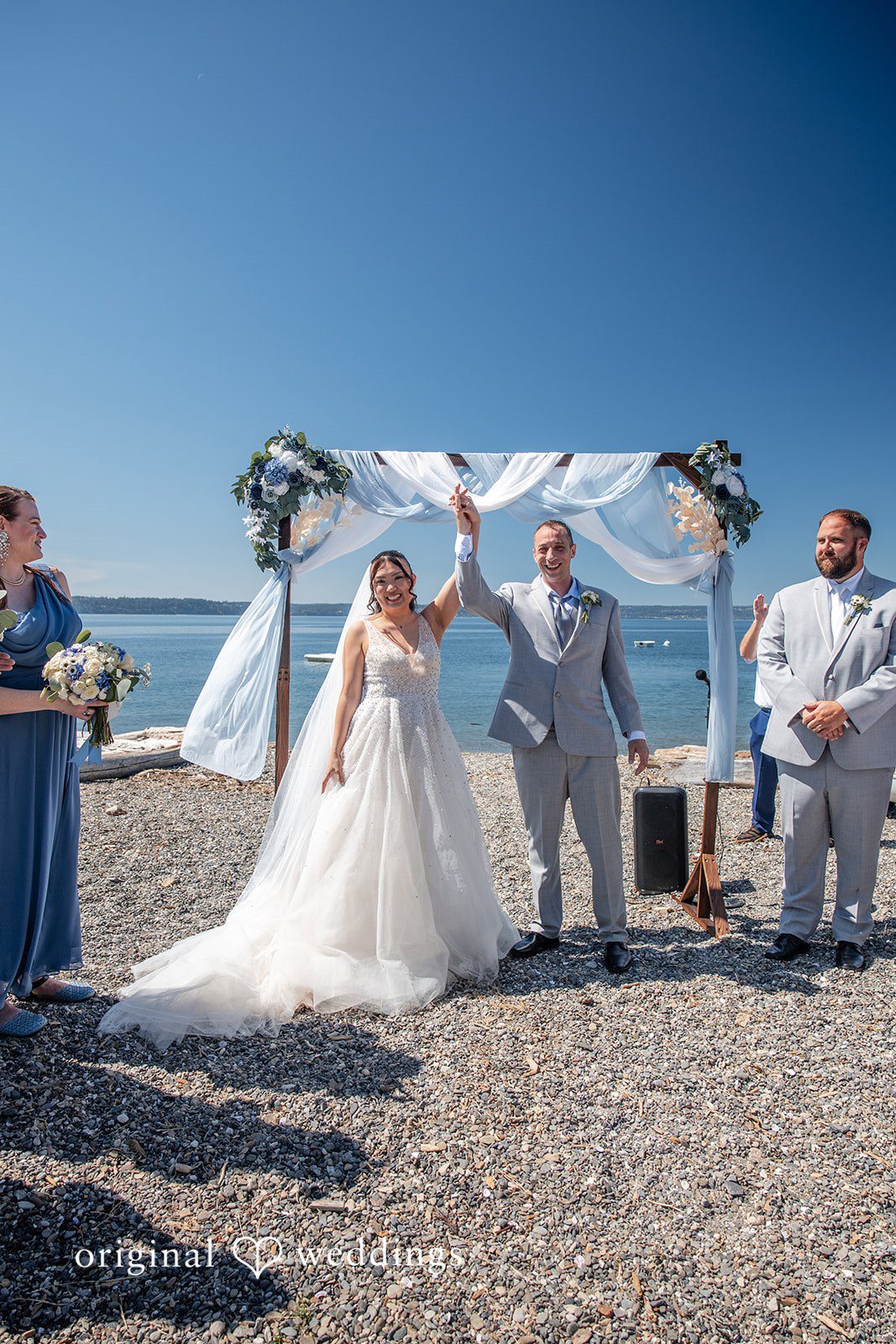 Kelly + John Couple standing under the ceremony arch at Mckees Beach