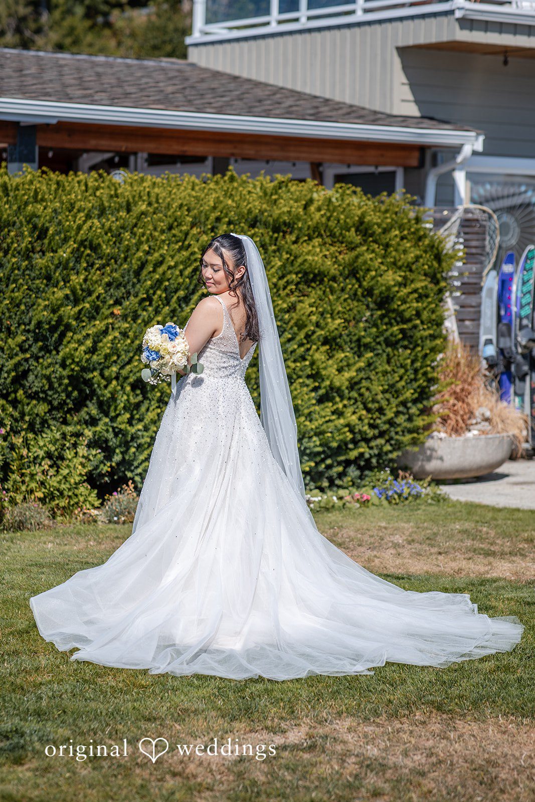 Kelly + John Bride standing in a garden in her gown