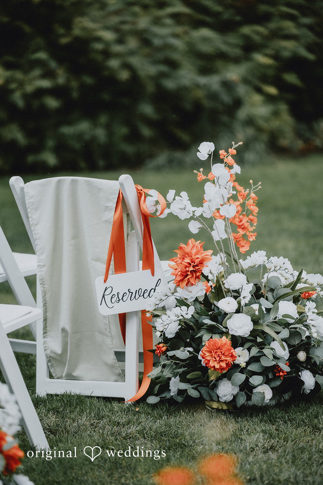 Benjamin + Tuan Ceremony chairs decorated with orange flowers at McMenamins Edgefield