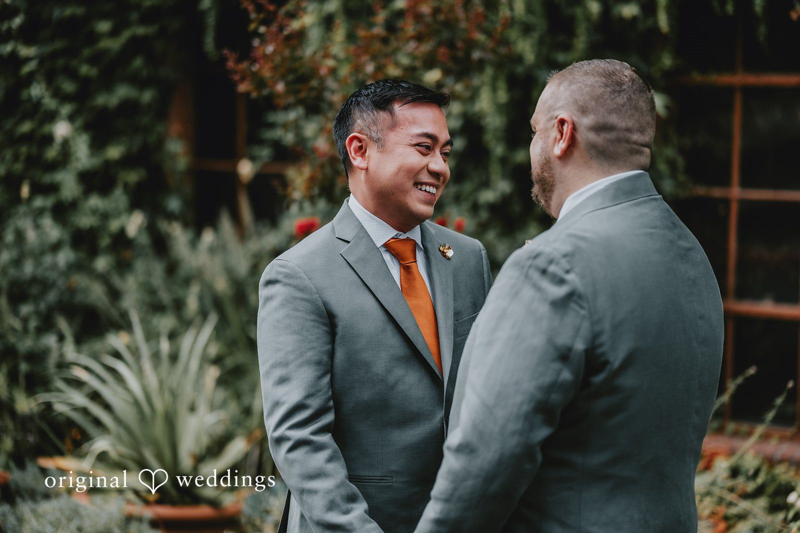 Benjamin + Tuan Grooms facing each other in the garden