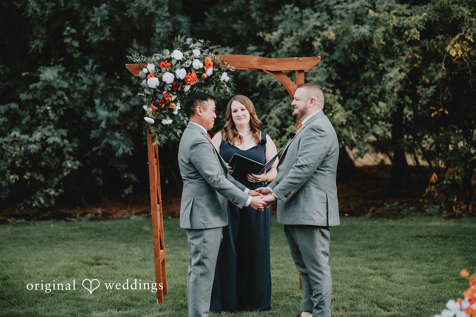 Benjamin + Tuan Couple standing under the wooden arch with the officiant