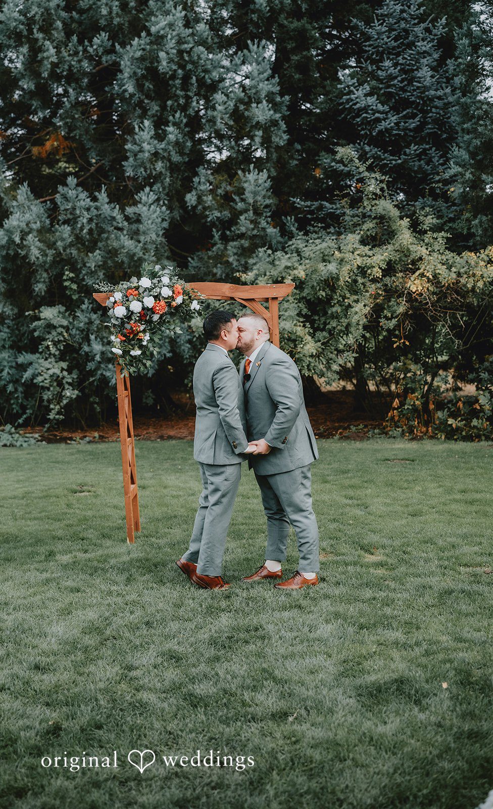 Benjamin + Tuan Benjamin and Tuan kissing under the ceremony arch