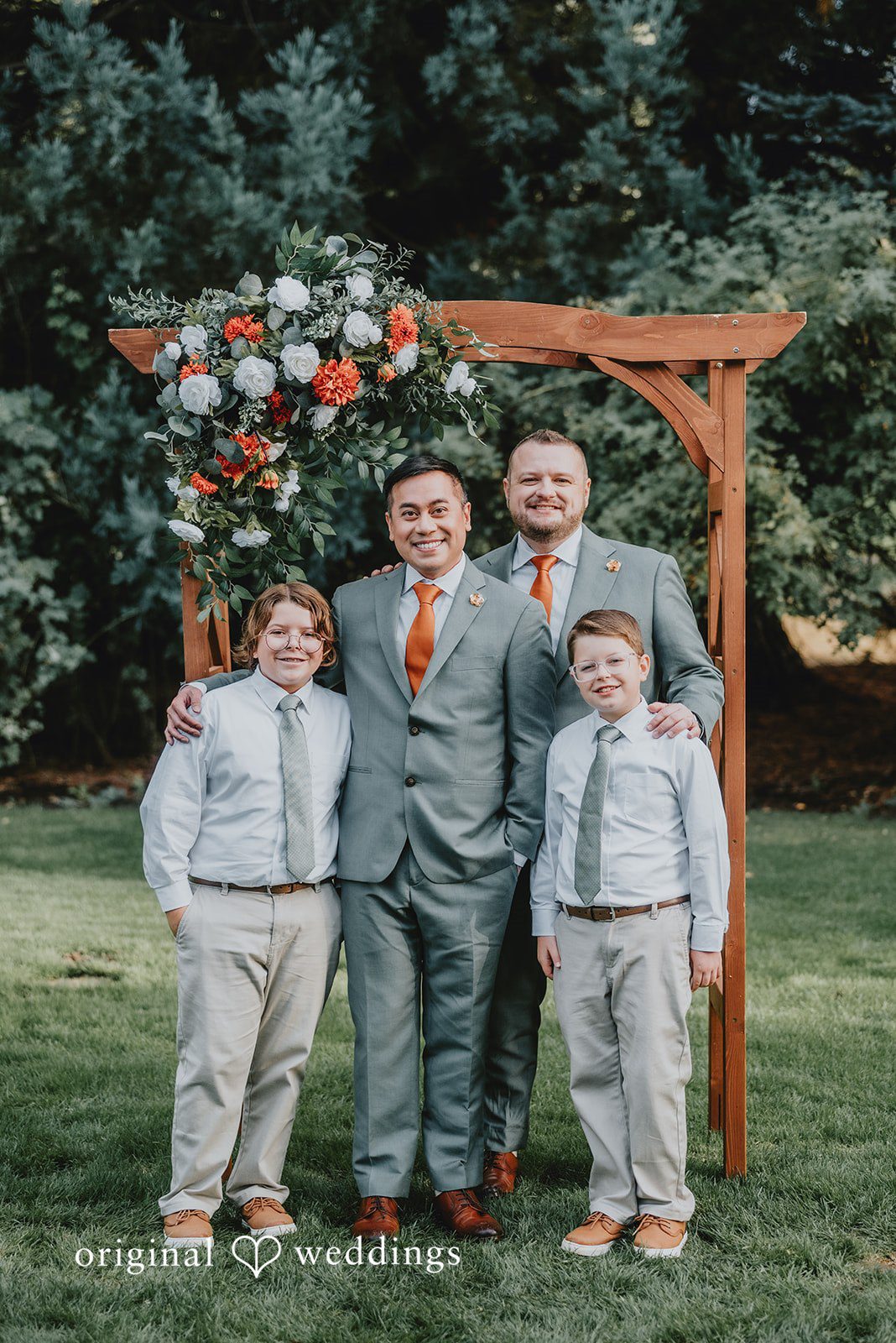 Benjamin + Tuan Family group photo with the grooms at the ceremony arch