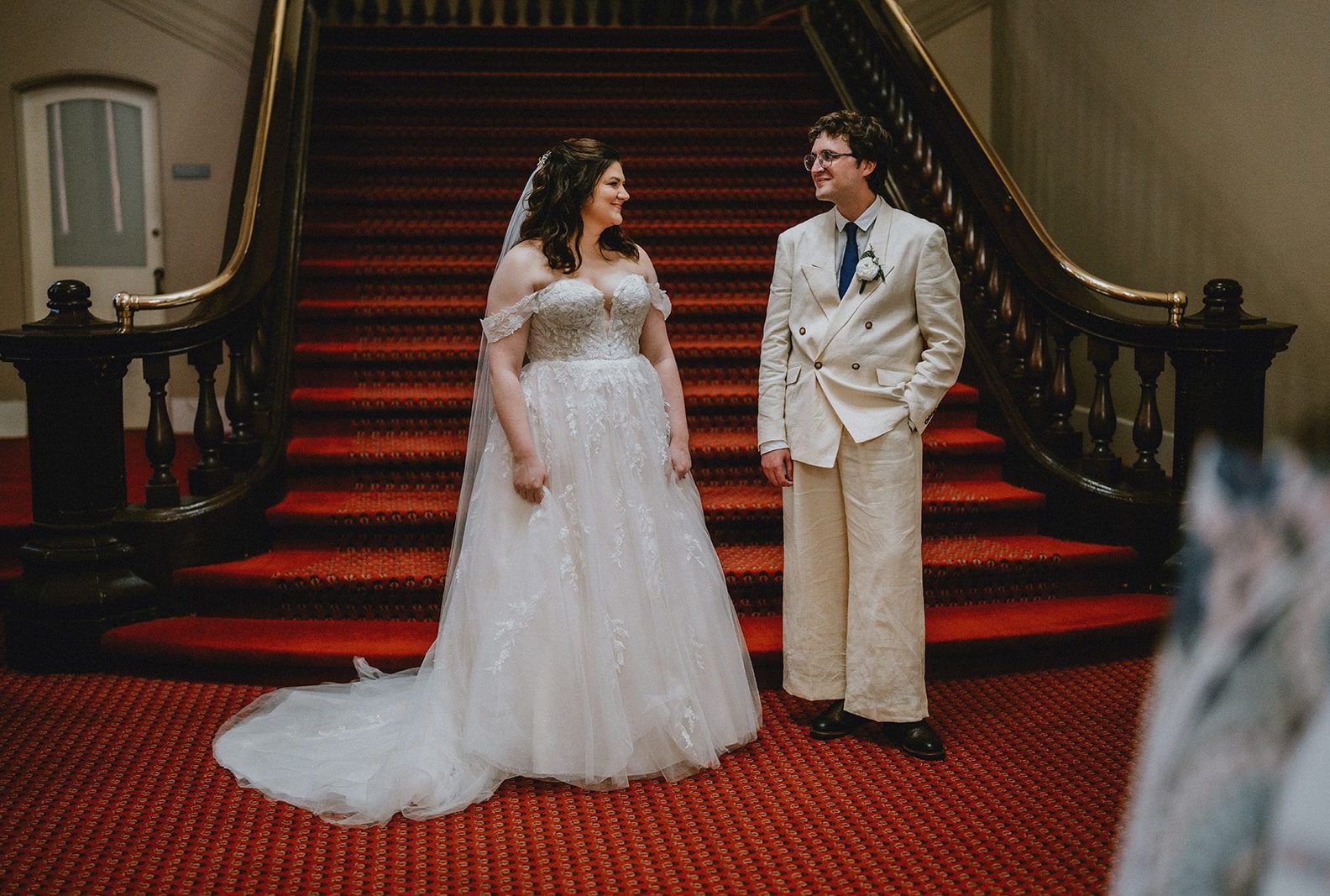 Bride and groom on the red staircase, captured by Boston wedding photographers from Original Weddings at Mechanics Hall