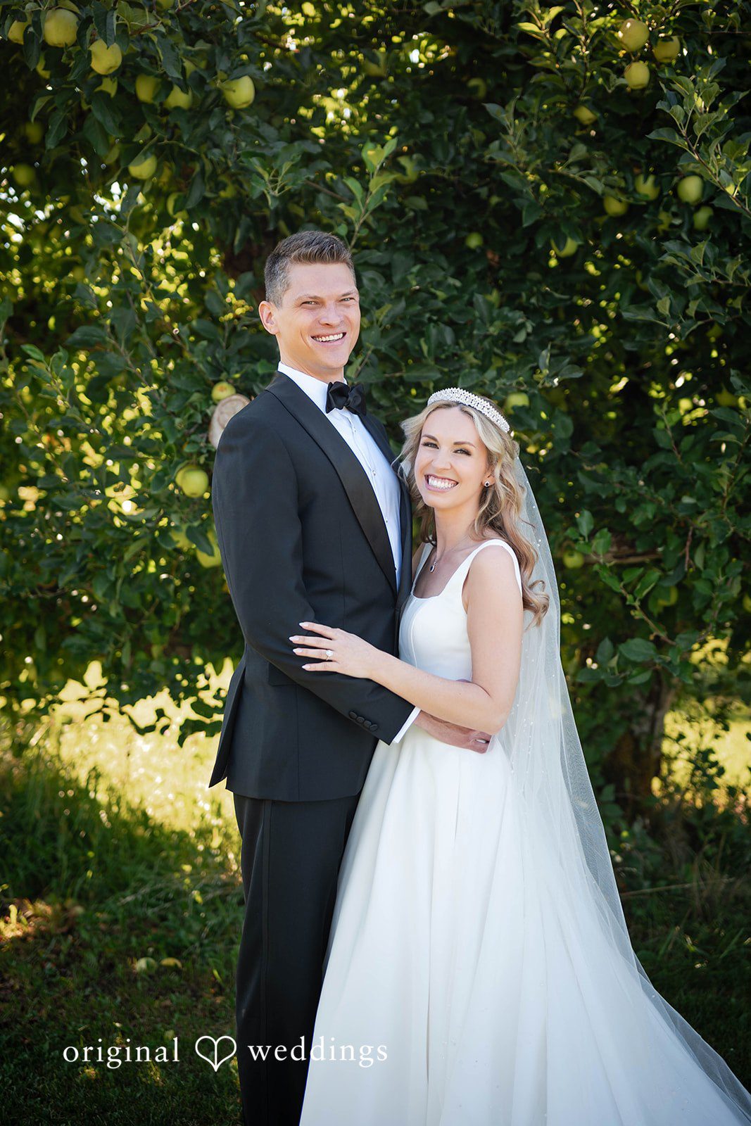 Couple posing together among the orchard trees