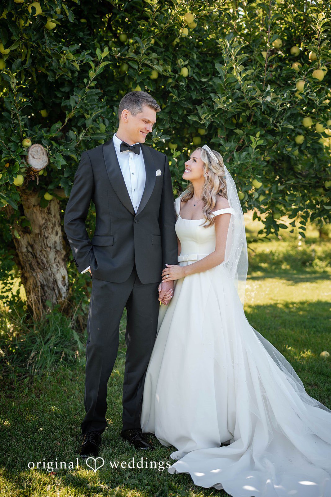 Couple close together under the fruit trees