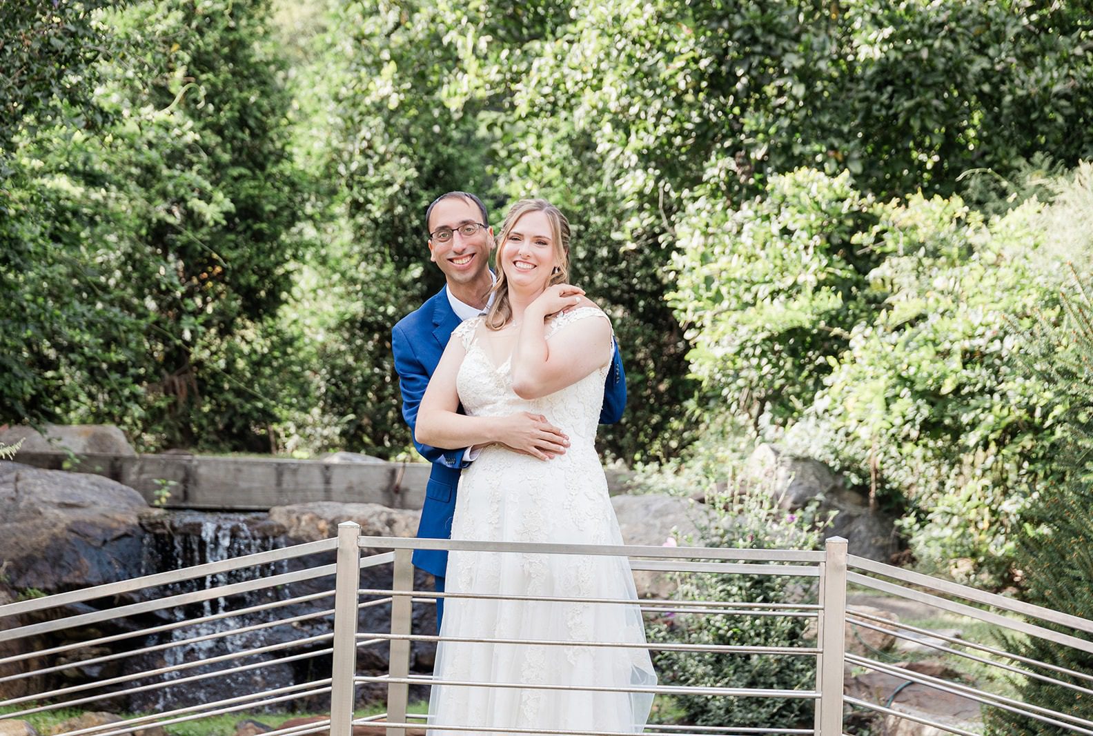 Groom hugging the bride on the garden bridge, captured by New York wedding photographers from Original Weddings at Travelers Rest