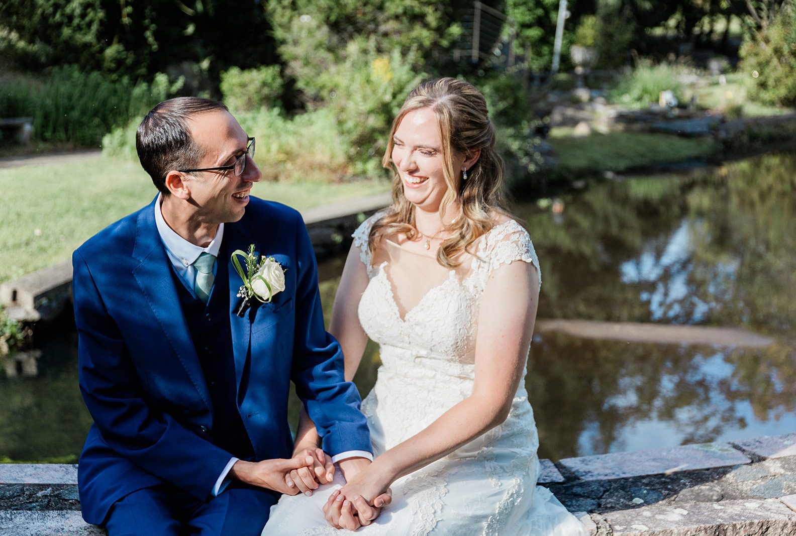 Bride and groom smiling by the pond, captured by New York wedding photographers from Original Weddings at Travelers Rest
