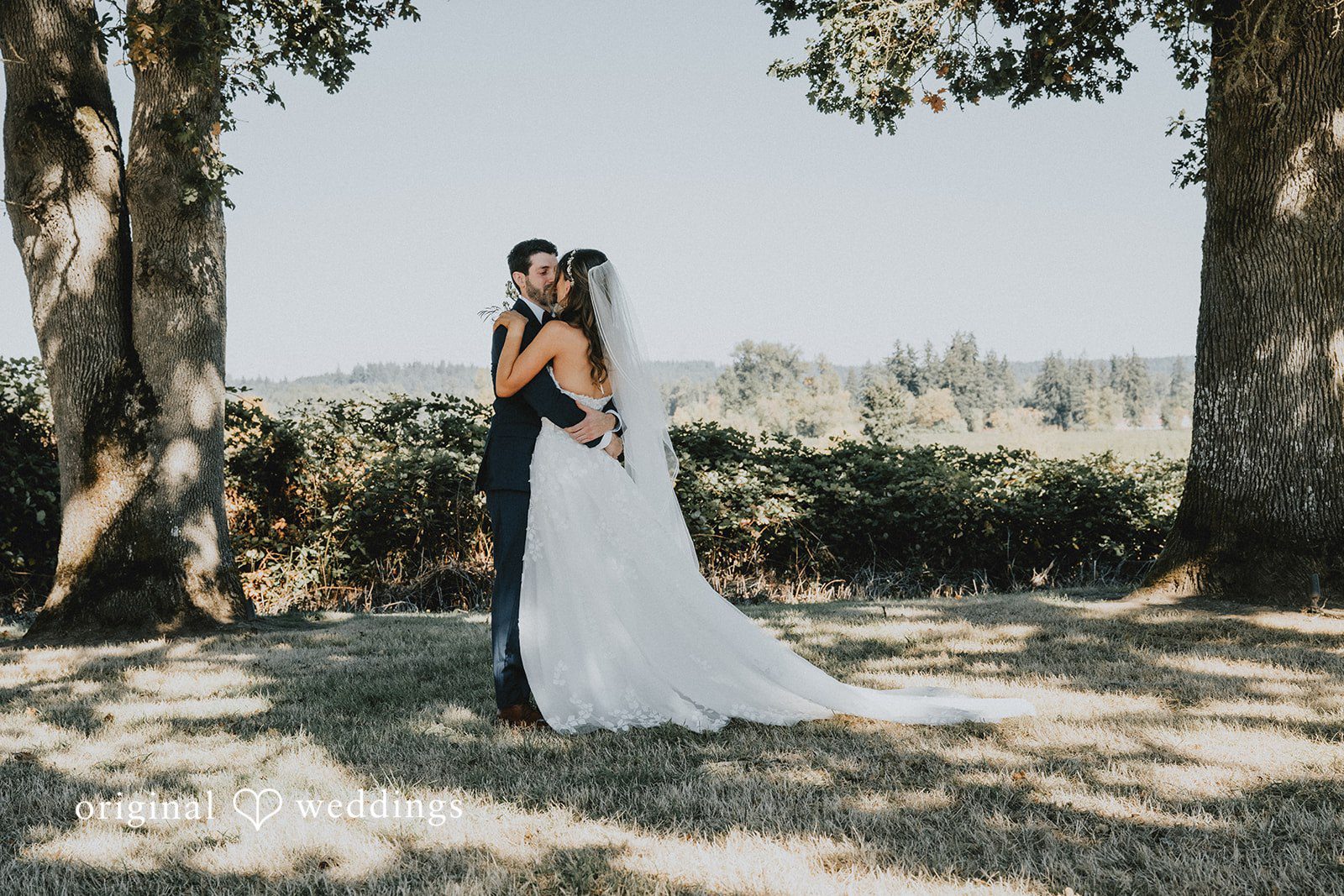 Couple embracing under the oak trees at Oak & Hood