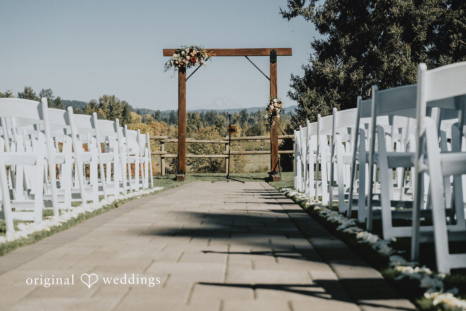 Outdoor ceremony arch with white chairs at Oak & Hood