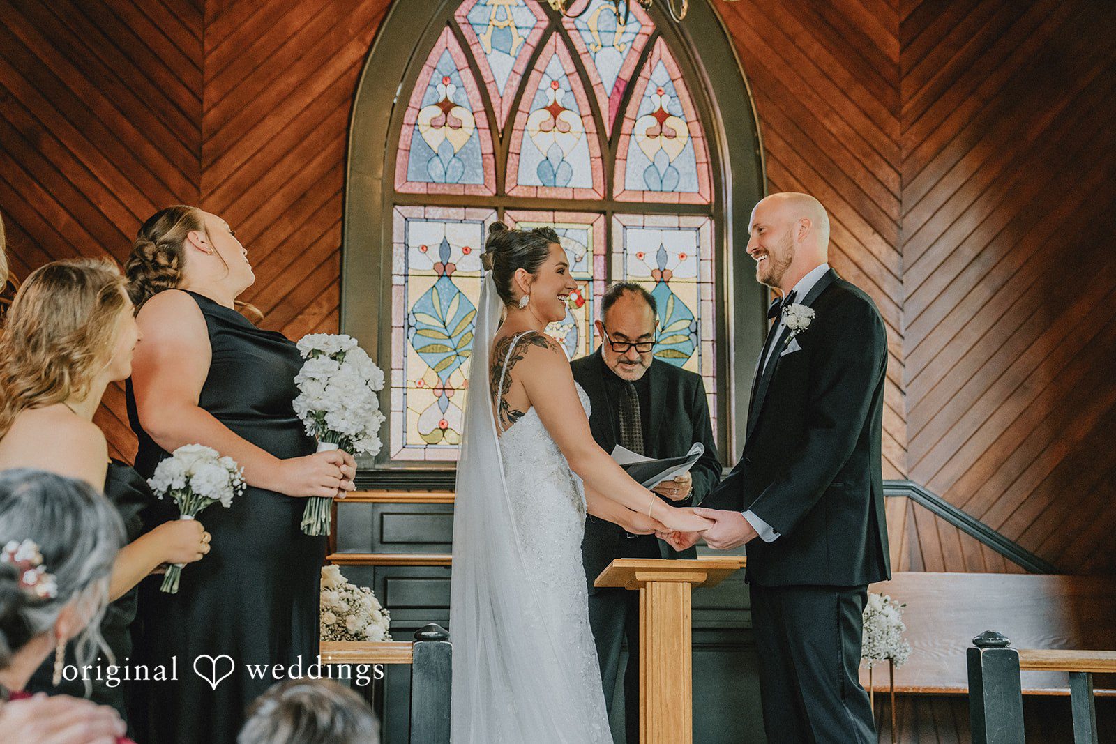Ashley + Forrest A bride and groom face each other while standing before an officiant during a church ceremony.