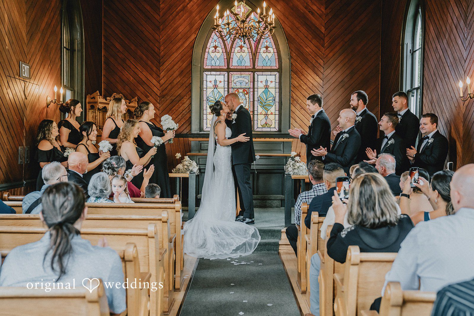 Ashley + Forrest A bride and groom stand together at the altar under the warm lighting of a church.
