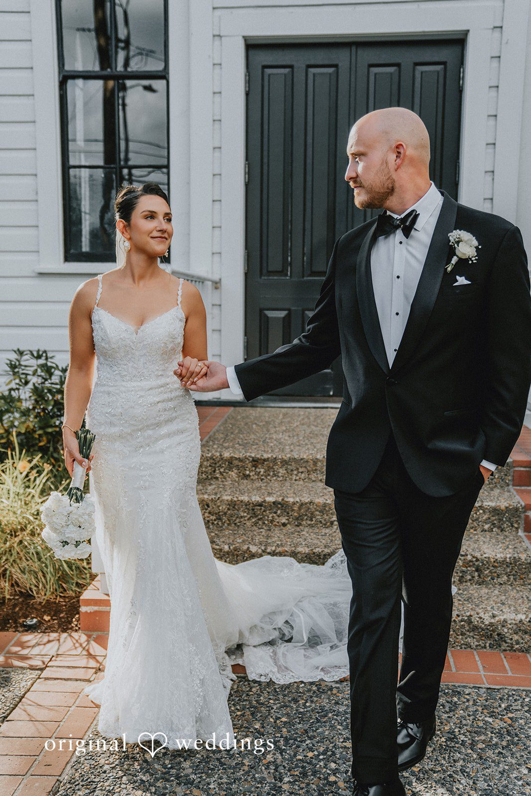 Ashley + Forrest A bride and groom hold hands while walking together along a path.