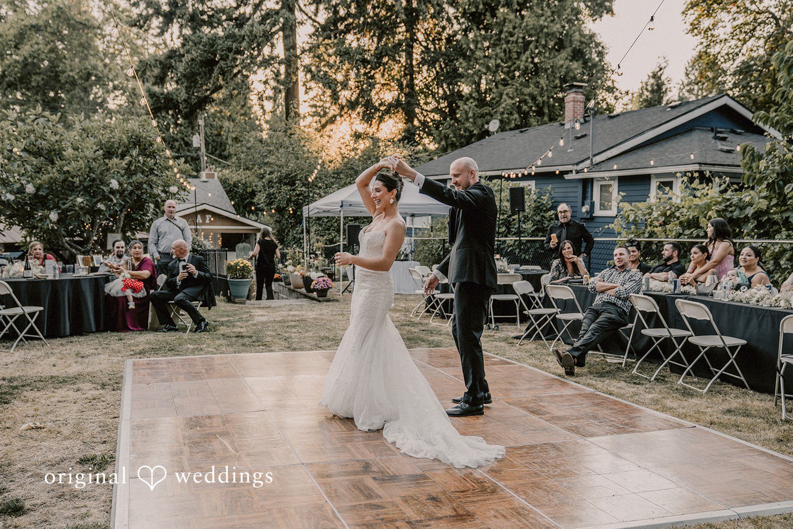Ashley + Forrest A bride and groom stand together on a dance floor with tables and tents nearby.