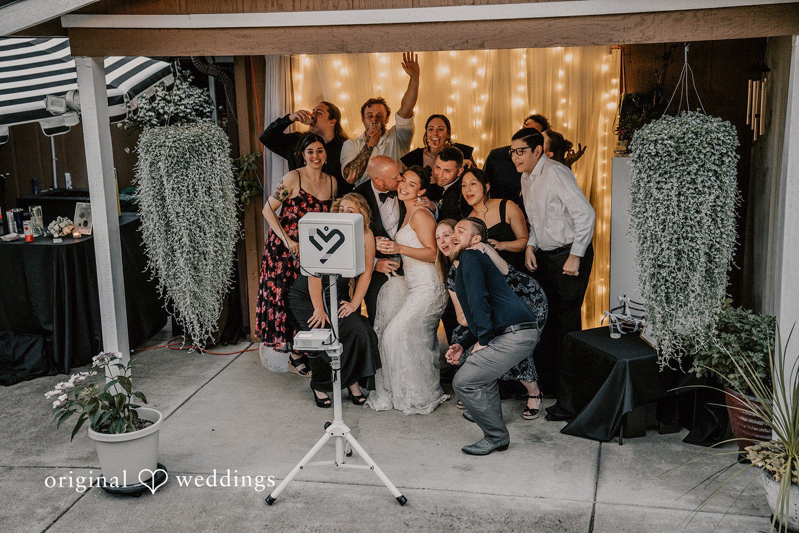 Ashley + Forrest A group of wedding guests pose together for a photo in front of a backdrop.