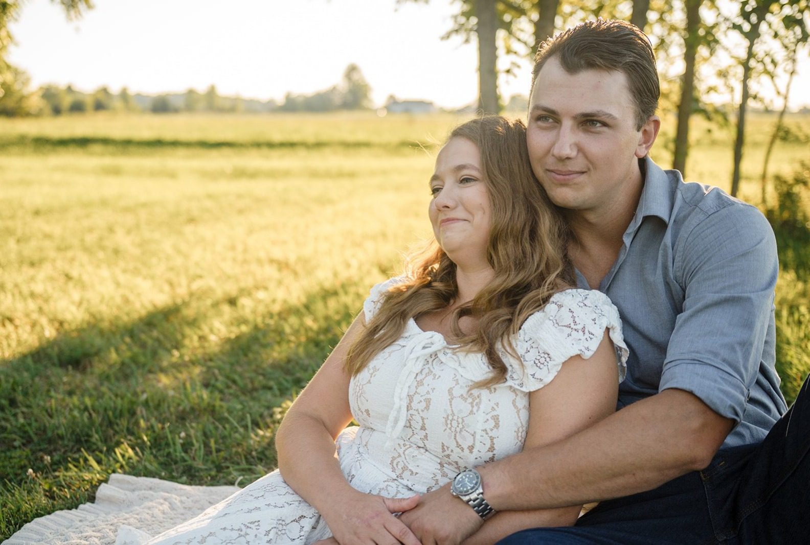 Madison and Maxx sitting together in the open field, captured by Engagement Photography Services from Original Weddings at their Ohio farm