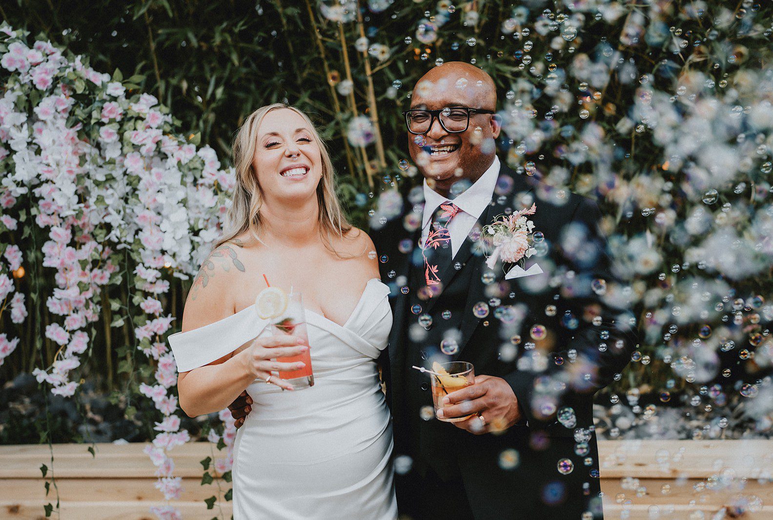 Bride and groom smiling under the floral arch, captured by Portland wedding photographers from Original Weddings at Chill Chill Chill