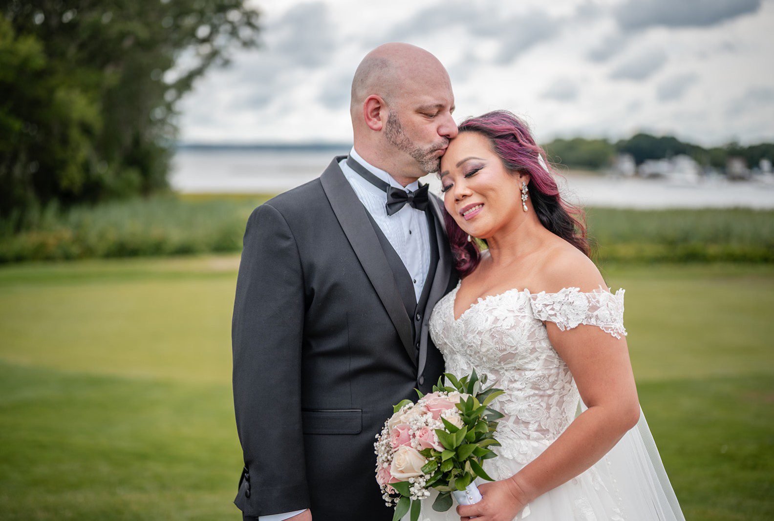 Bride and groom smiling together on the waterfront lawn, captured by Providence wedding photographers from Original Weddings at Harbor Lights