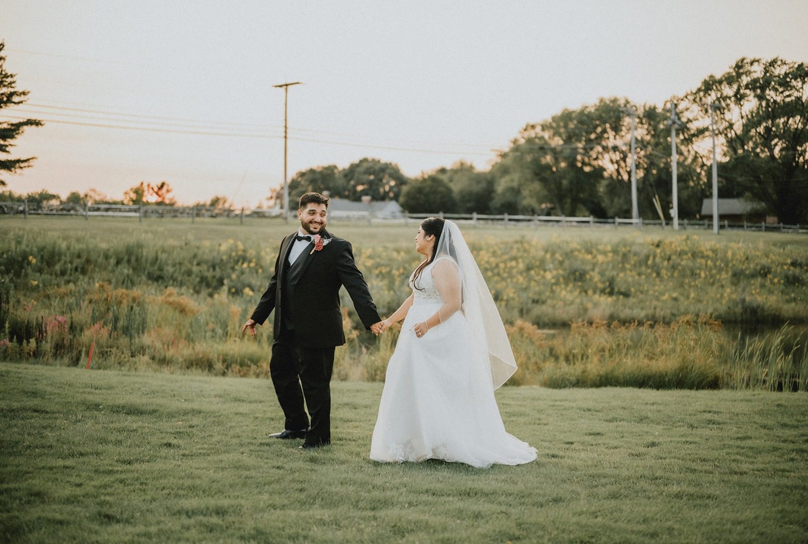 Couple walking through the field, captured by Providence wedding photographers from Original Weddings at The Barn at Blackstone National
