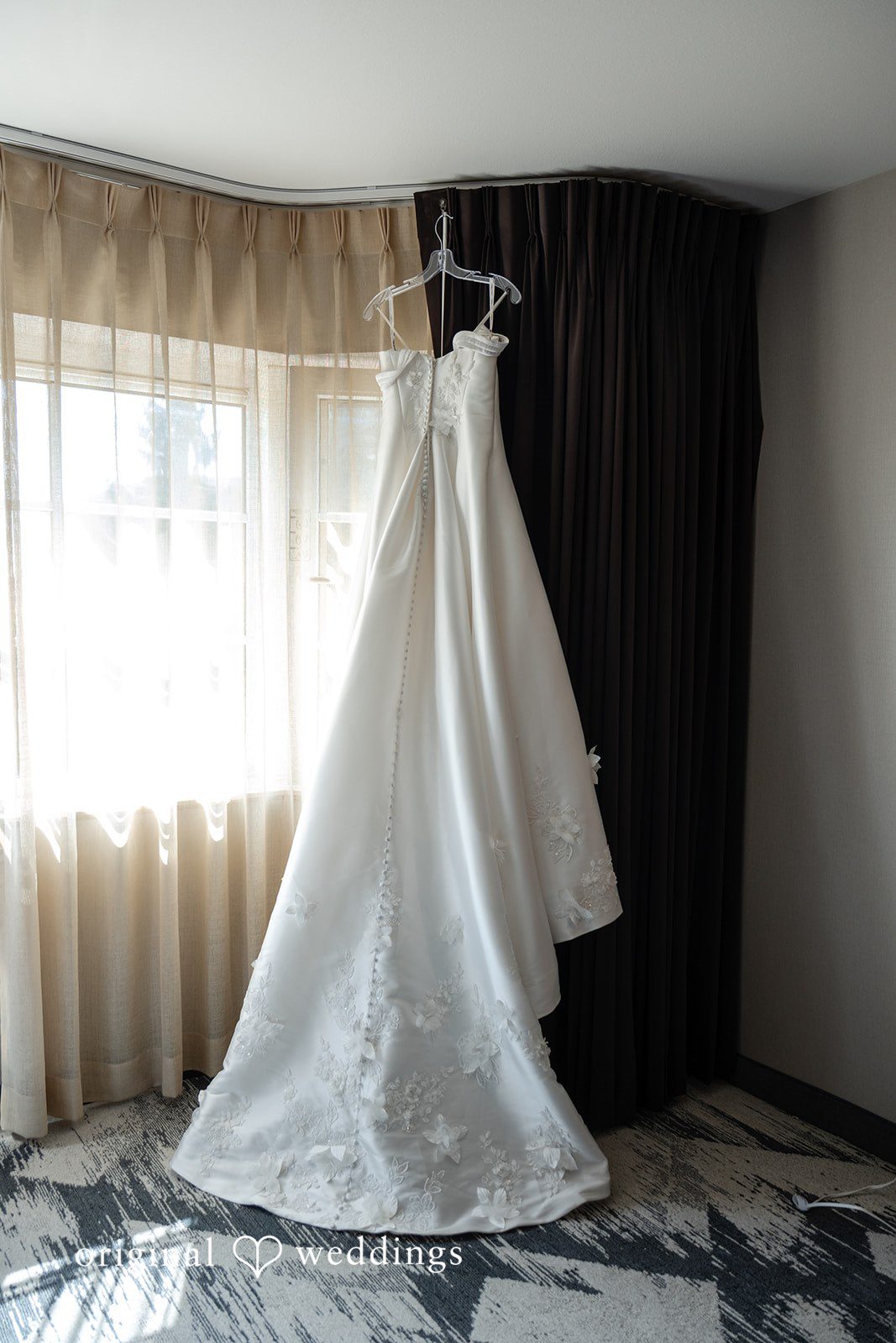 Danielle's wedding dress hanging by the window