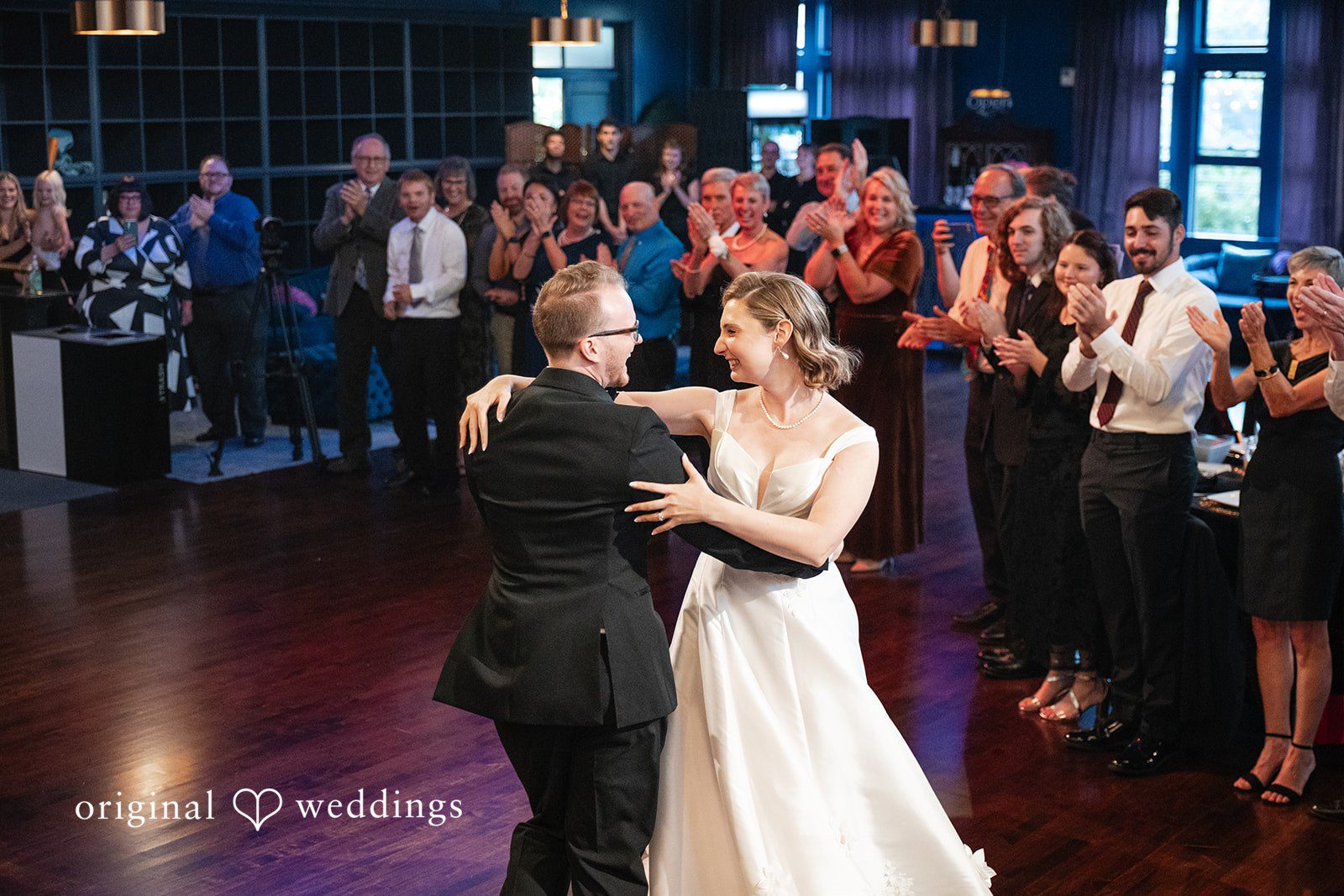 Bride and groom dancing with guests watching