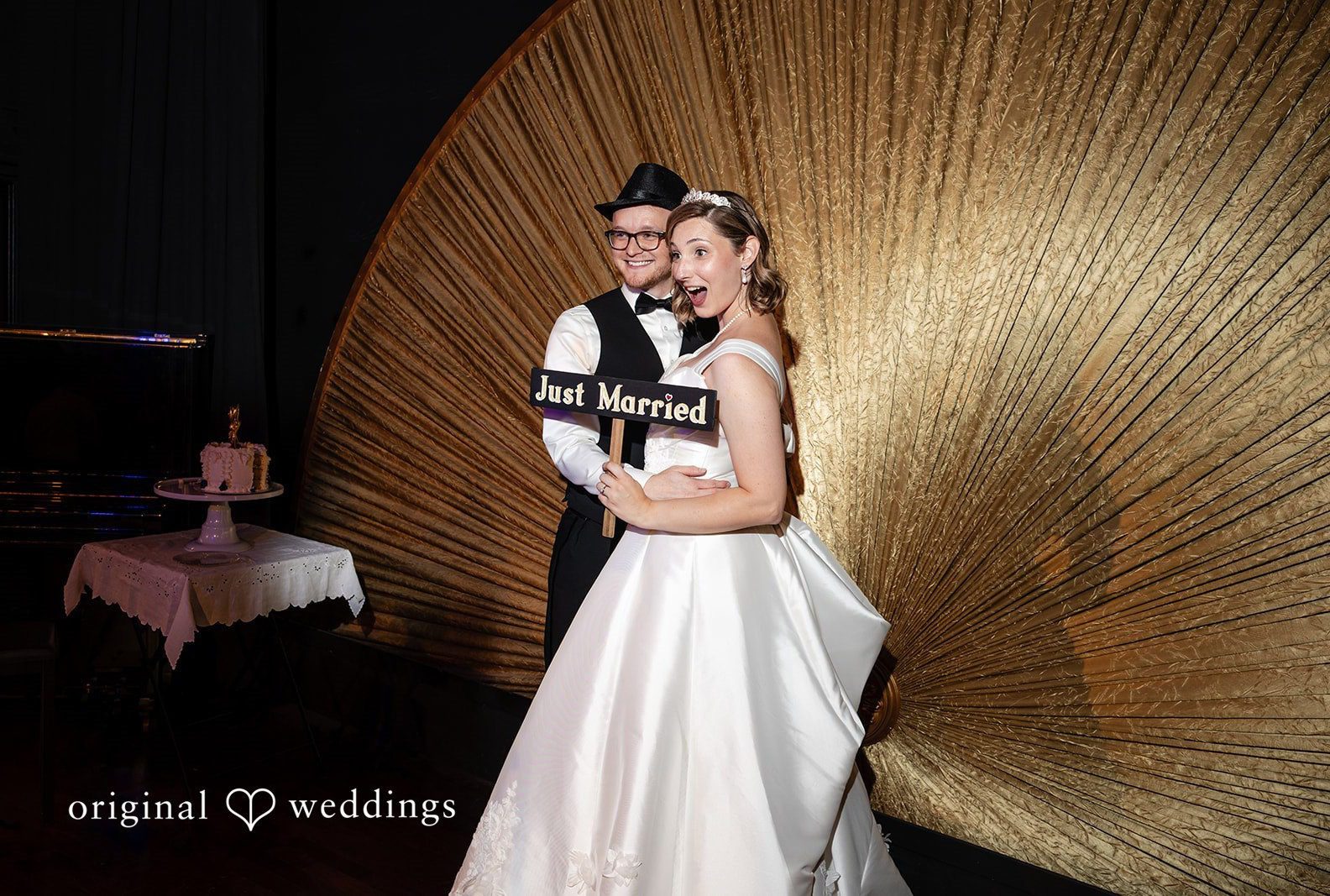 Danielle and Anthony embracing by the gold fan, captured by Seattle wedding photographers from Original Weddings at Reverie Ballroom