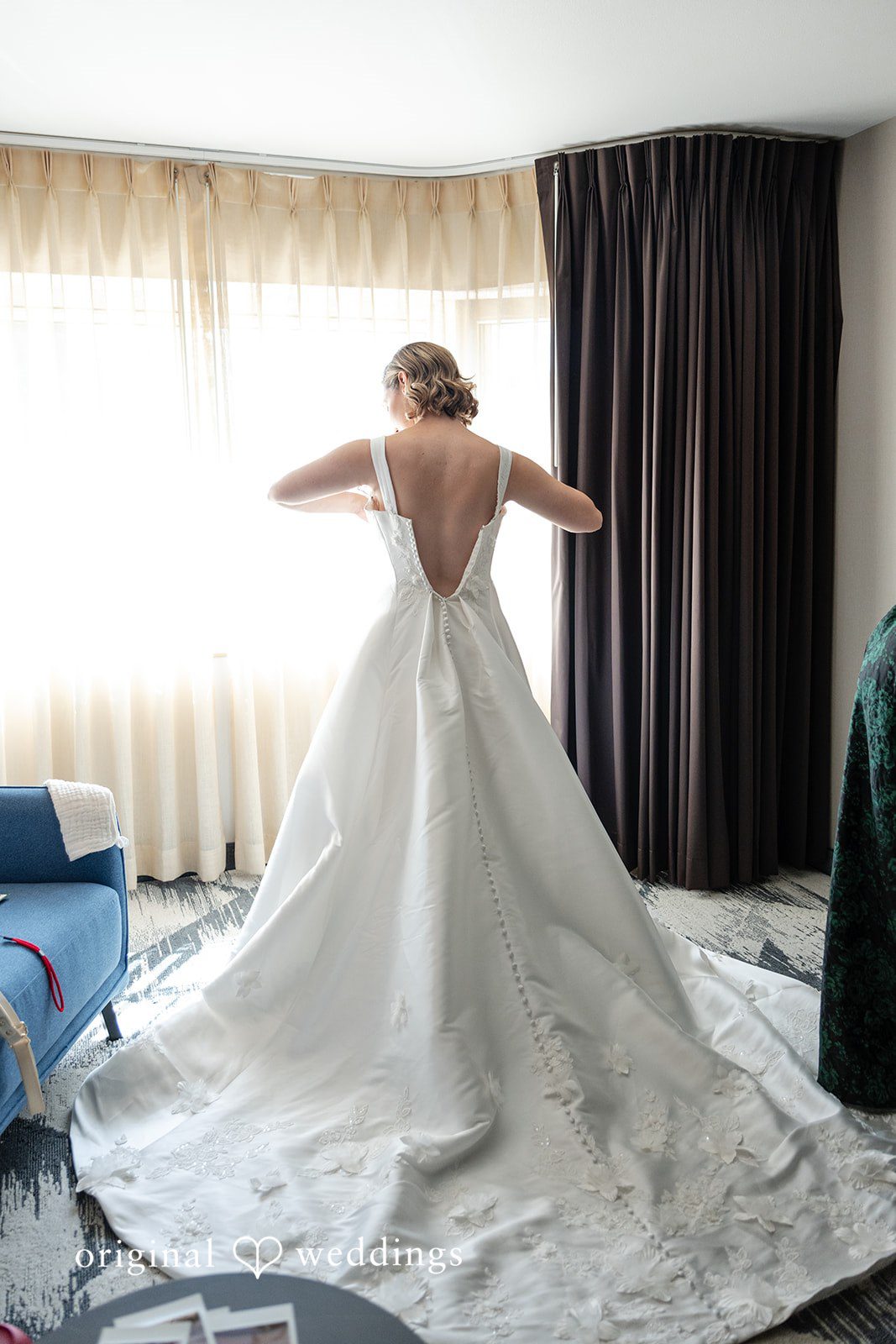 Bride by the window showing the back of her dress