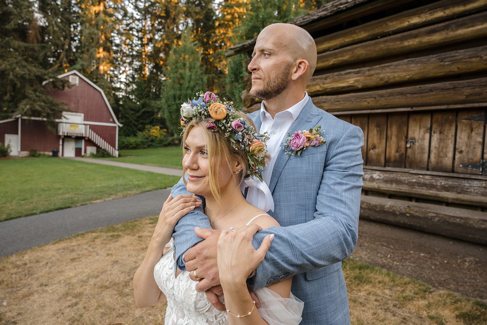 Bride and groom embracing by the rustic log cabin, captured by Seattle wedding photographers from Original Weddings at Robinswood House