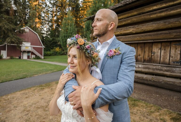 Bride and groom embracing by the rustic log cabin, captured by Seattle wedding photographers from Original Weddings at Robinswood House
