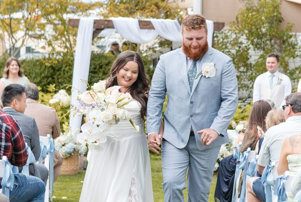 Newlyweds walking back up the aisle after their vows, captured by Seattle wedding photographers from Original Weddings at Roche Harbor Resort