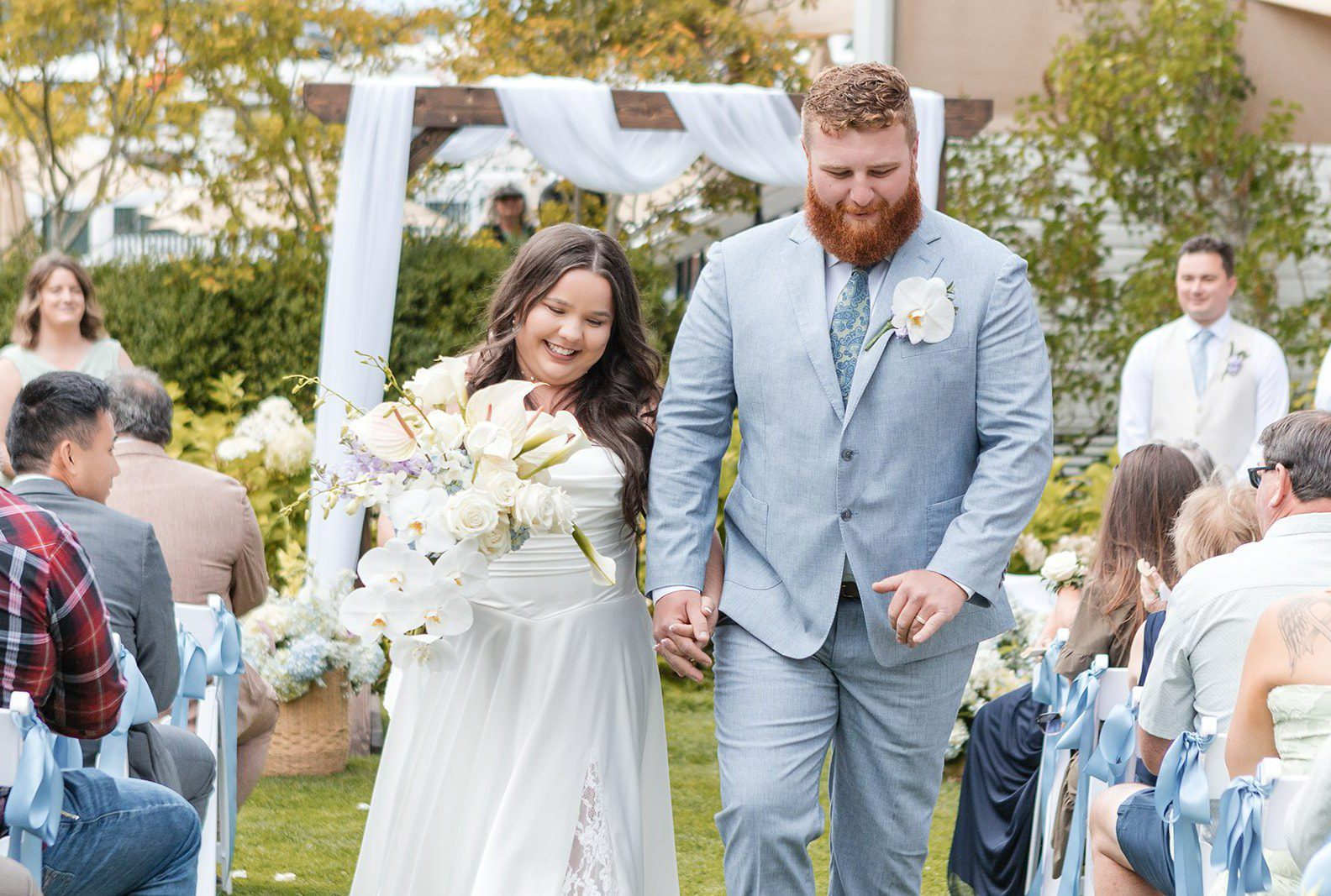 Newlyweds walking back up the aisle after their vows, captured by Seattle wedding photographers from Original Weddings at Roche Harbor Resort