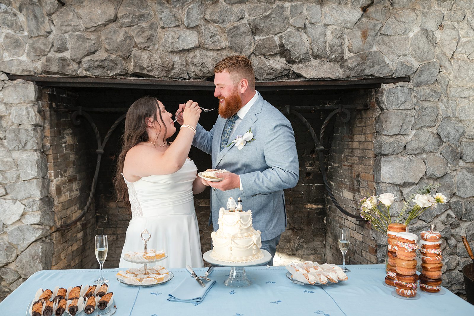 roche-harbor-resort-timeless-seattle-emma-chase-emma-chase-040-14 Newlyweds cutting the cake by the stone fireplace