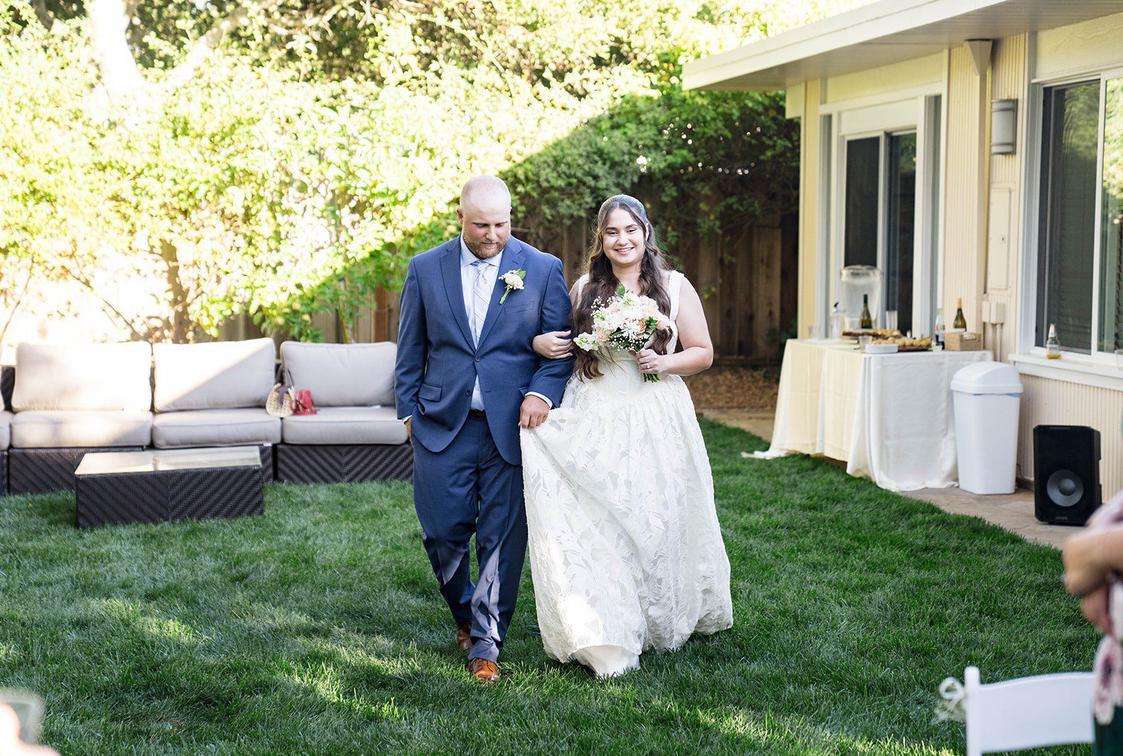 Bride and groom walking together across the backyard lawn, captured by San Francisco wedding photographers from Original Weddings at a California backyard wedding