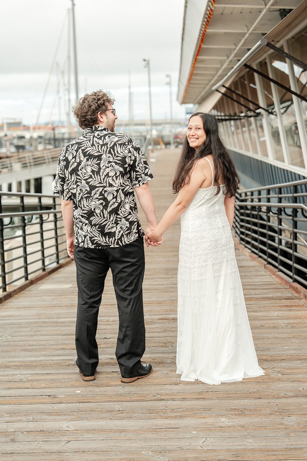 scotts-seafood-grill-bar-timeless-san-francisco-libby-ethan-p008-12 Bride and groom holding hands on the boardwalk at Scott's Seafood Grill & Bar