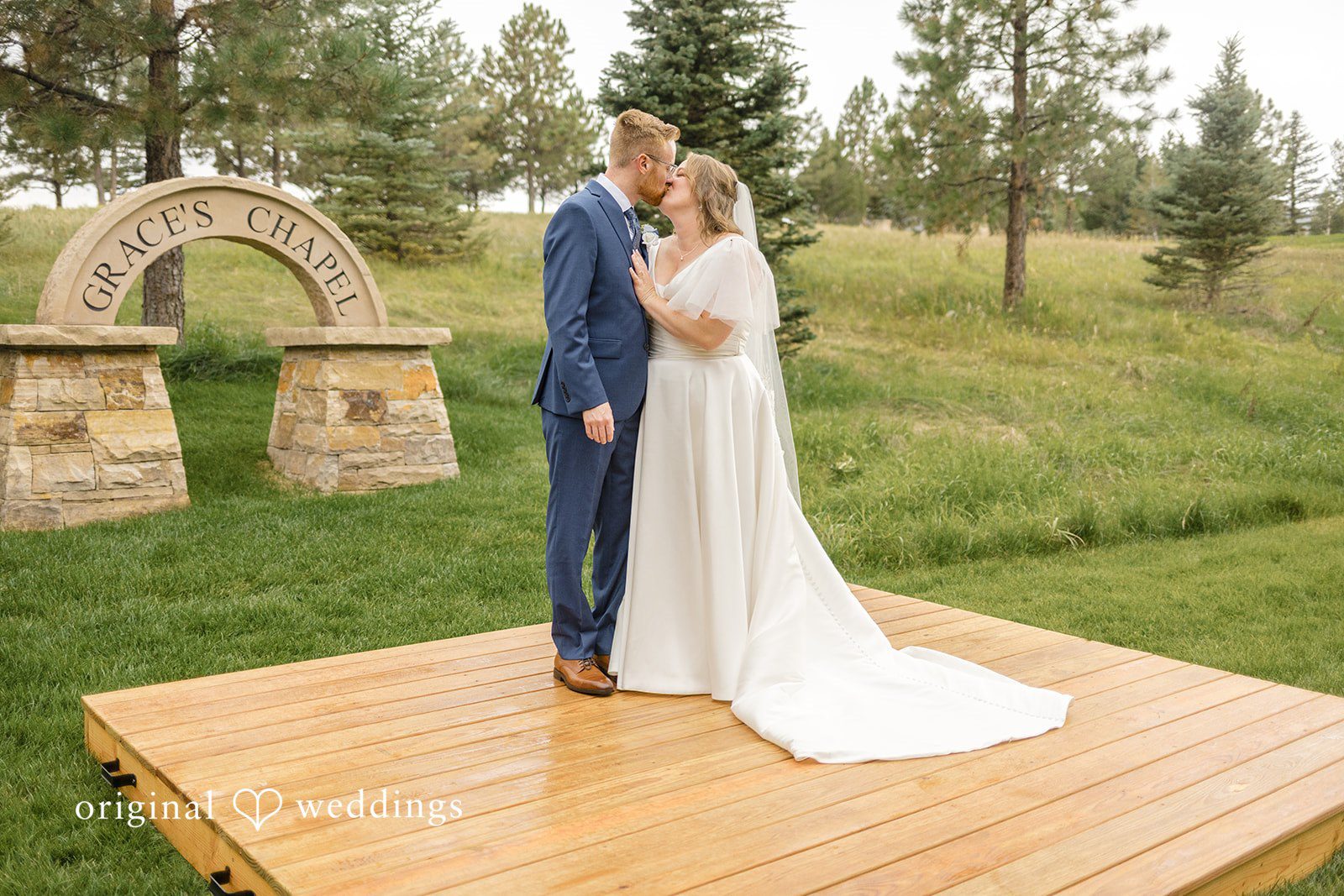 Faith + Brandon Couple standing on a wooden platform in a mountain meadow at Spruce Mountain Ranch