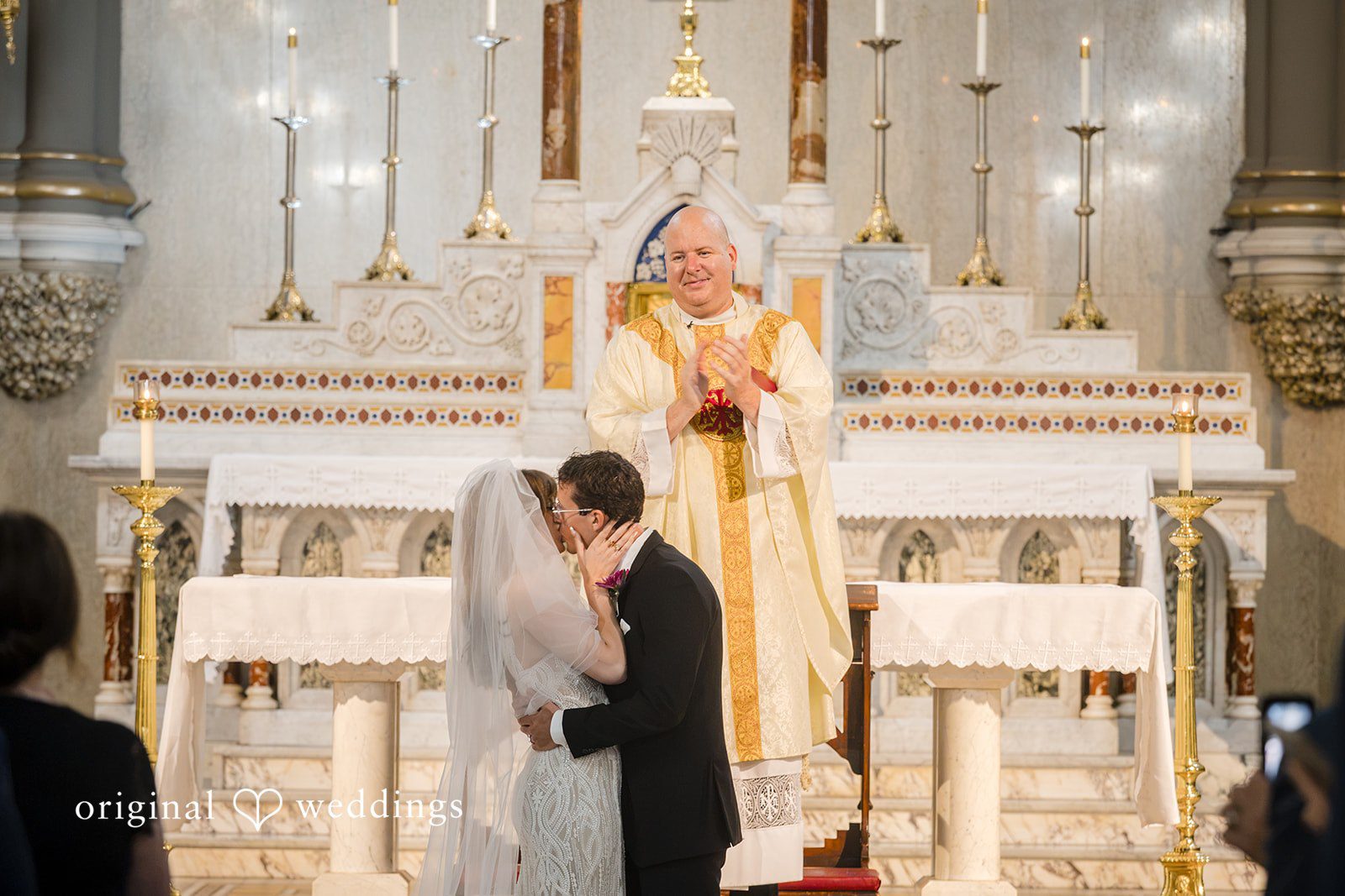 Priest blessing the couple at the altar of St John the Evangelist Catholic Church