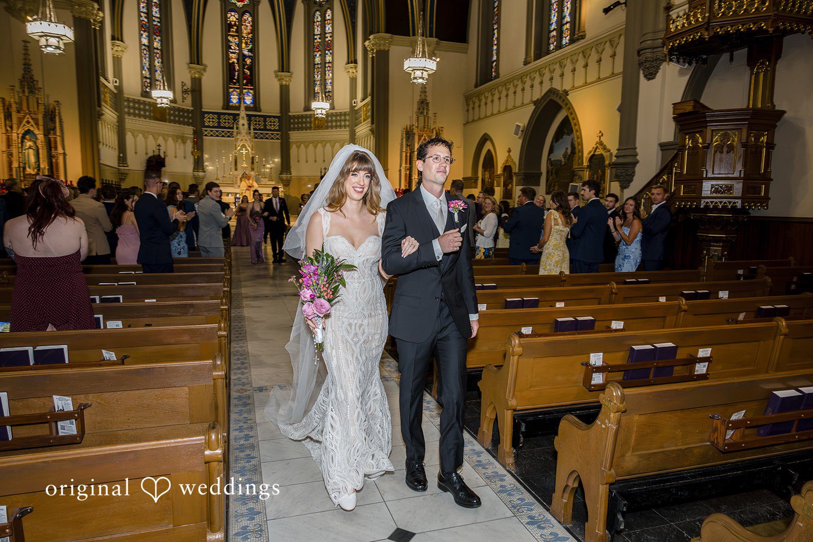 Couple walking back down the aisle as newlyweds at St John the Evangelist Catholic Church
