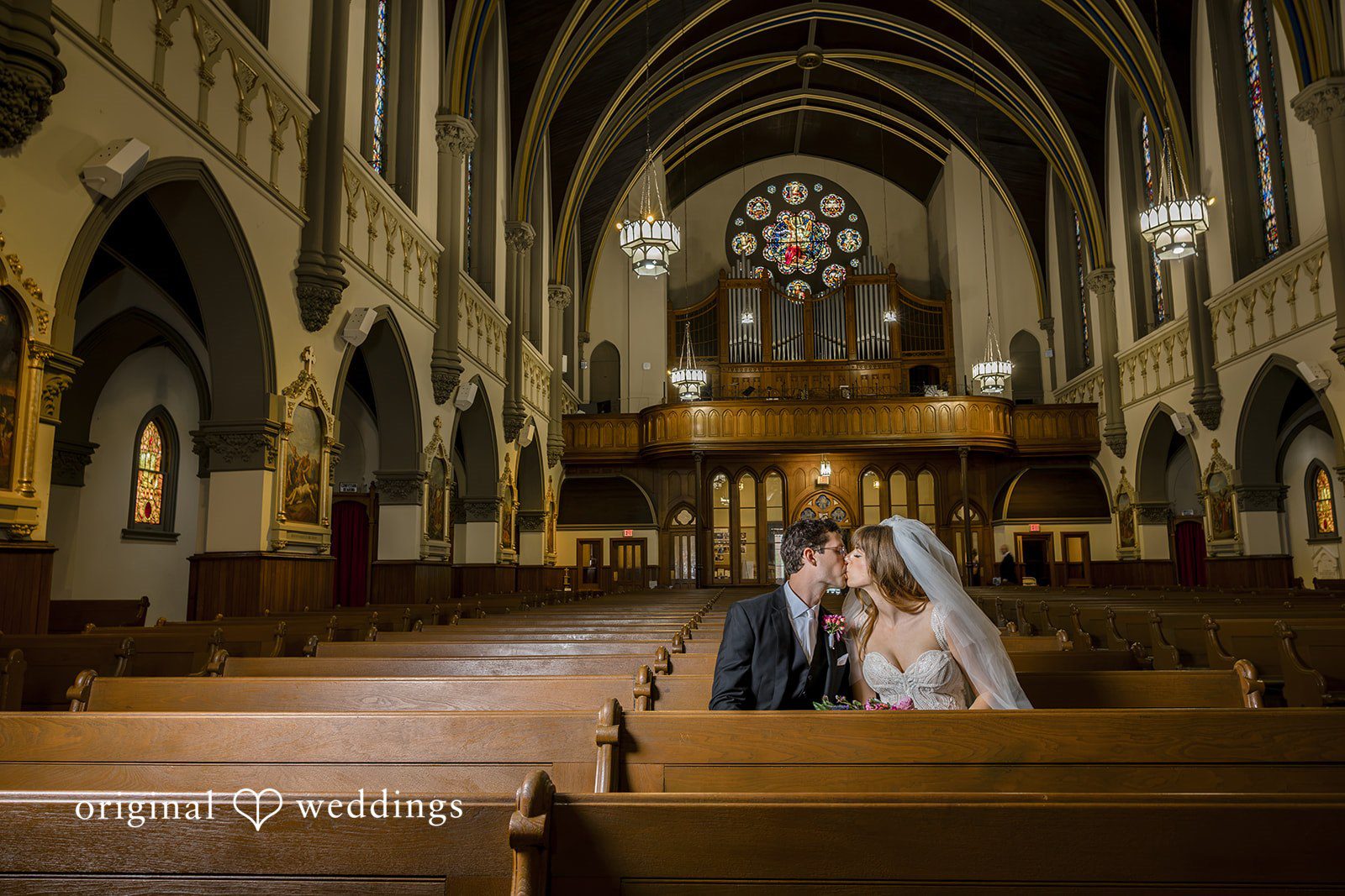 Couple sharing a kiss in the church pews at St John the Evangelist Catholic Church