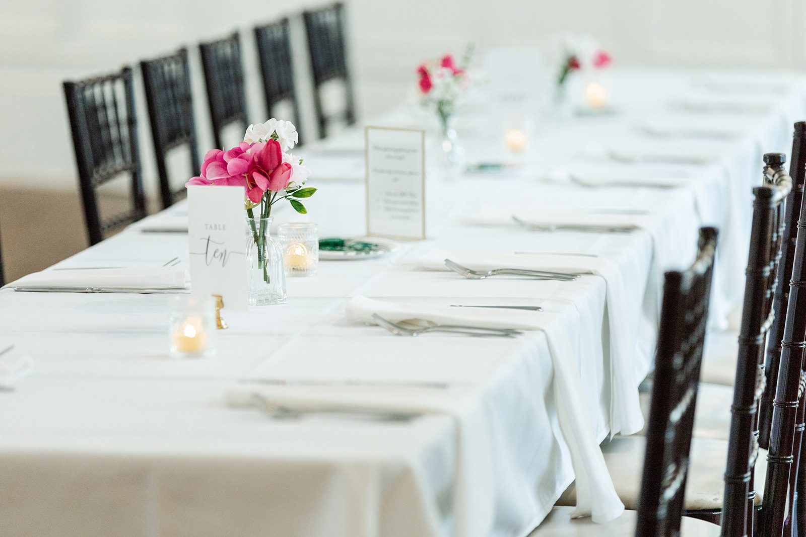 Reception table with white linens and pink flowers at St. Paul College Club Reception table with white linens and pink flowers at St. Paul College Club