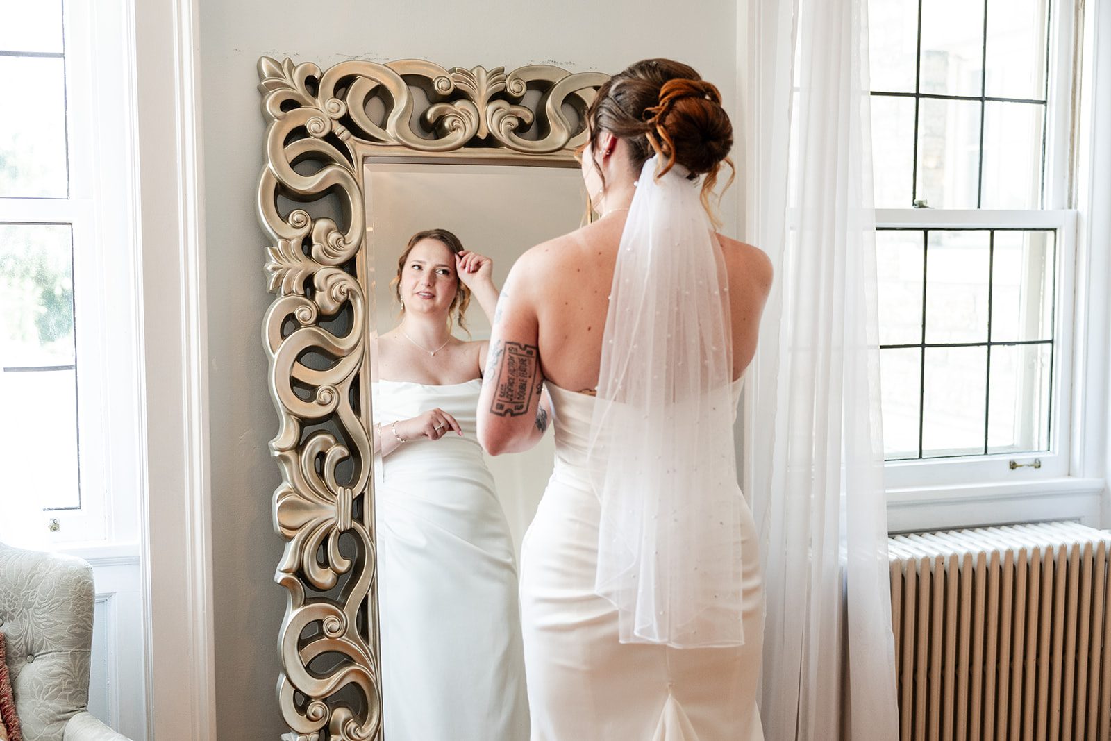 Bride adjusting her veil in the mirror at St. Paul College Club Bride adjusting her veil in the mirror at St. Paul College Club