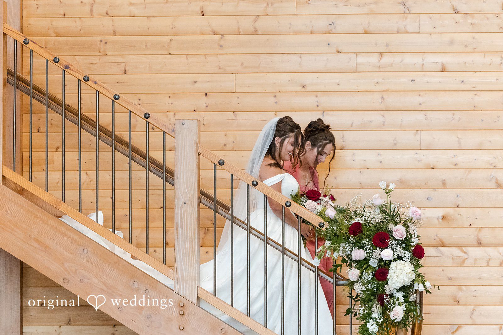 The bride and her maid of honor walk down the stairs