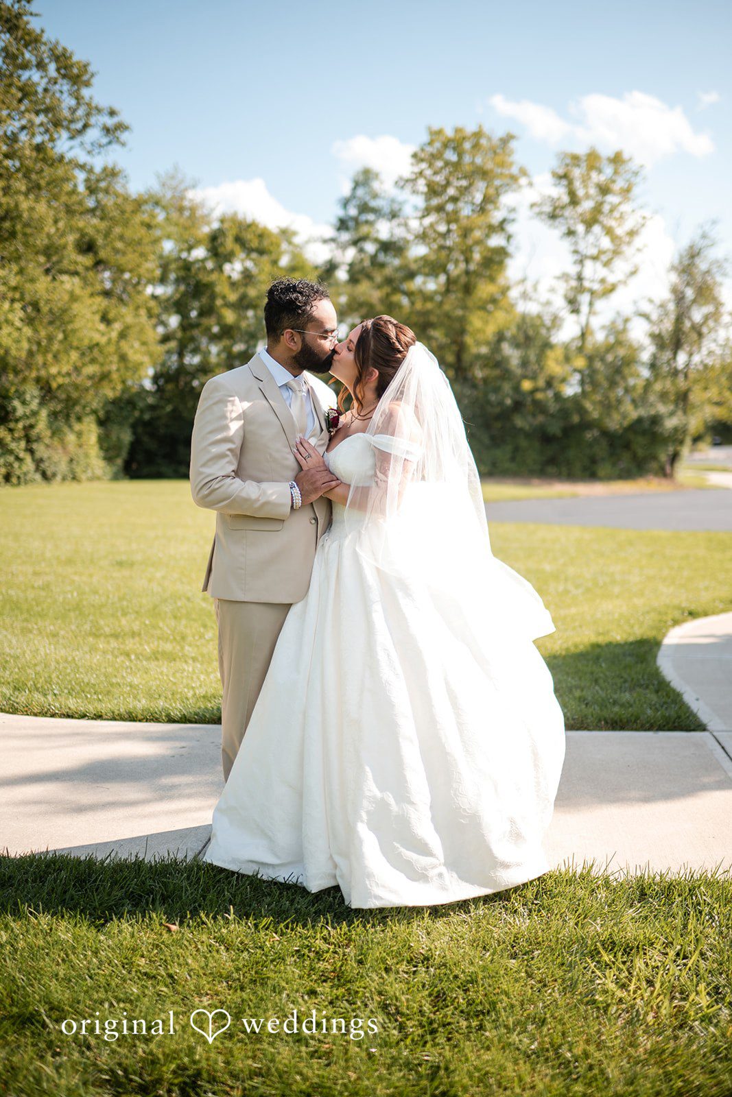 The couple shares a kiss outdoors