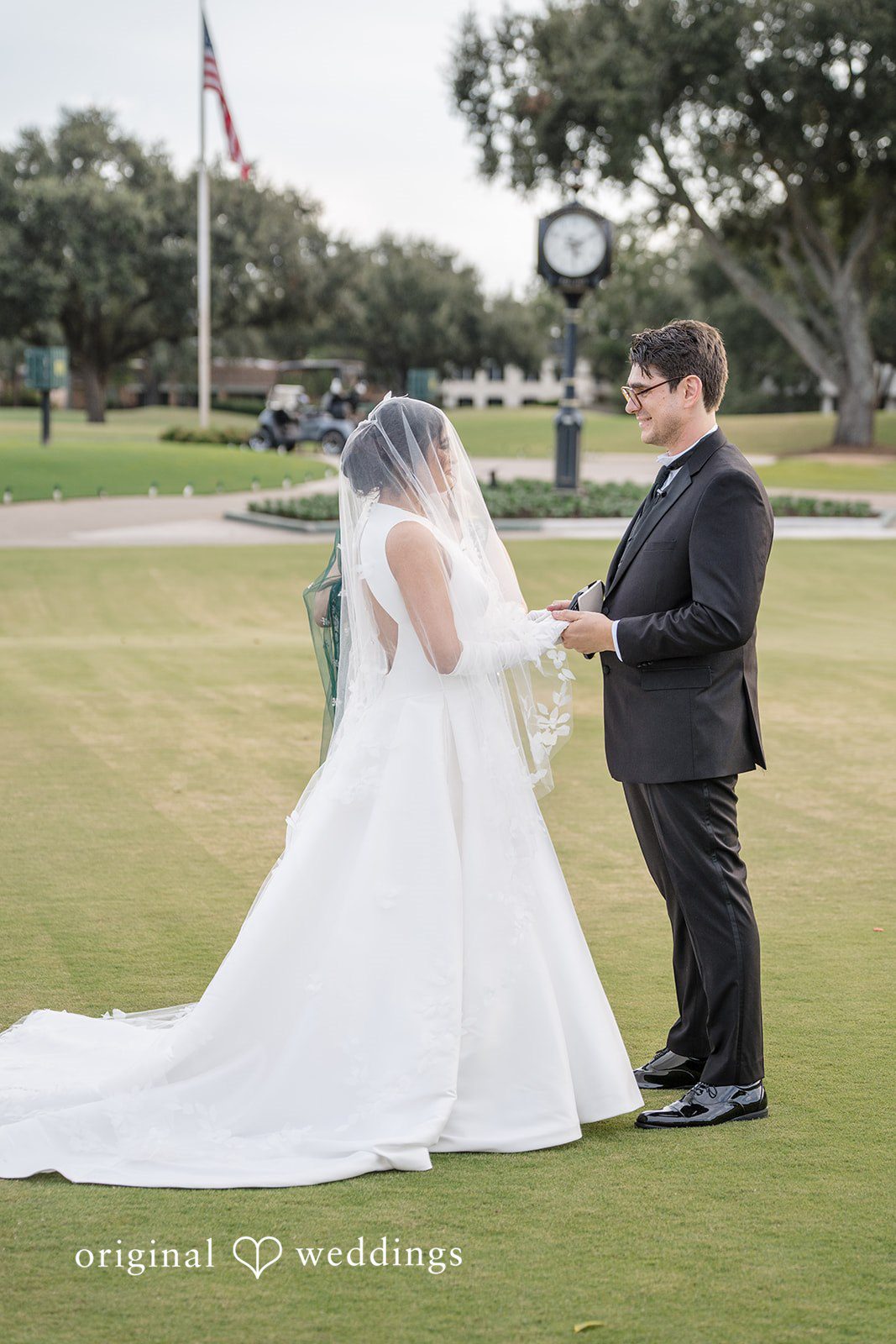 Nicholas + Nisha Bride and groom holding hands while standing together on a lawn.