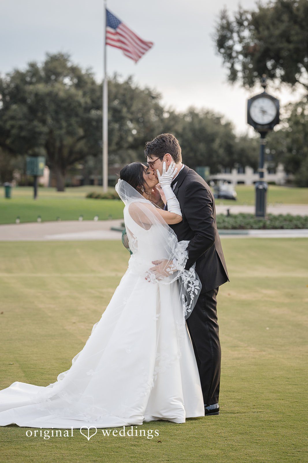 Nicholas + Nisha Bride and groom embracing on a grassy lawn.