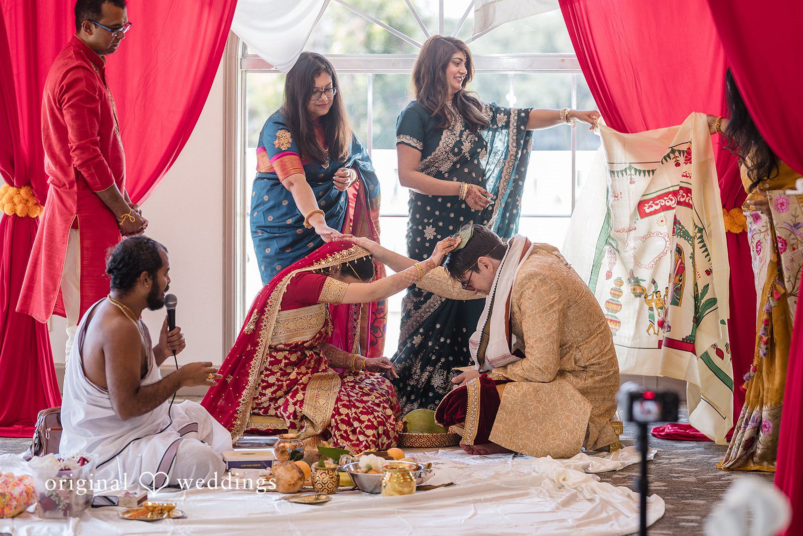 Nicholas + Nisha Group of people participating in a wedding ritual with colorful decorations.