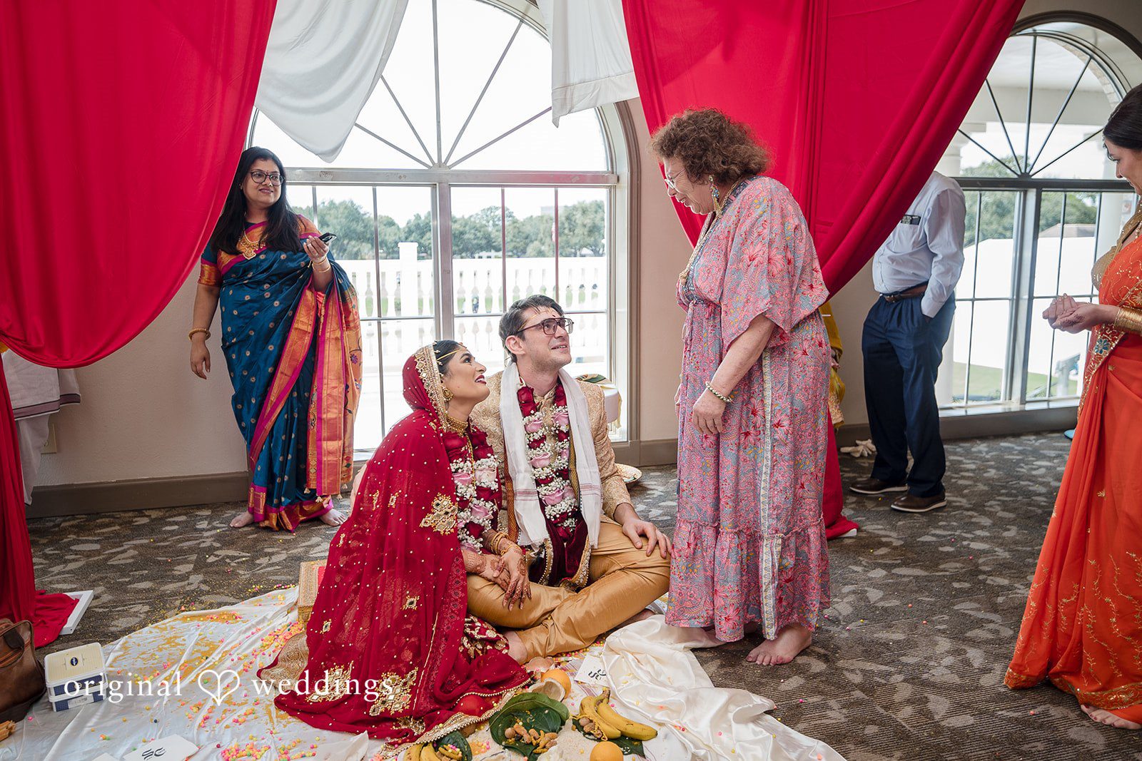 Nicholas + Nisha Participants wearing traditional garments interacting during a wedding ritual.