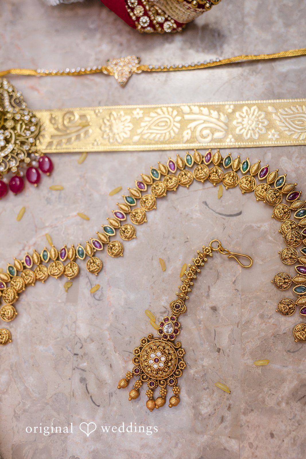 Nicholas + Nisha Intricate gold wedding jewelry, featuring a traditional headpiece resting on patterned fabric.