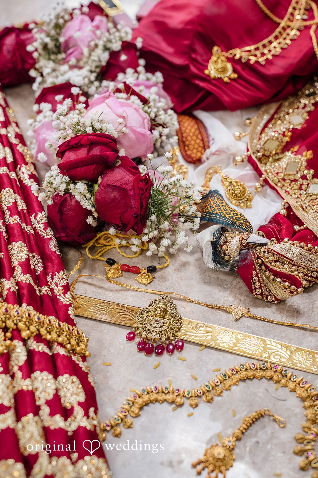 Nicholas + Nisha Vibrant red wedding attire adorned with gold embroidery and decorative floral accents.